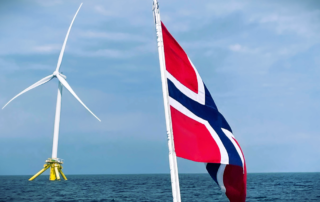 Floating offshore wind turbine in Norway with the Norwegian flag in the foreground, symbolizing the country's renewable energy transition.